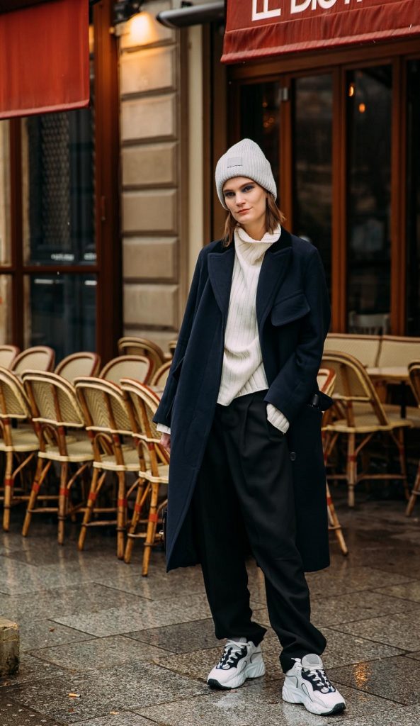 picture of a women standing in front a coffee shop wearing stylish clothes and sneakers