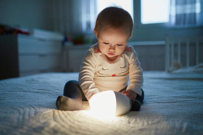 baby sitting on bed with nightlight