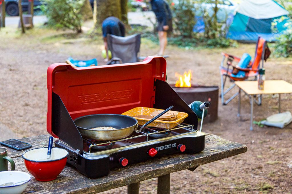 We’re kicking things off with the basics – whether you’re grilling a few juicy pieces of meat or warming up some vegetables, you’ll need a stove to do so. It’s singlehandedly one of the most important items in your camp kitchen inventory. Nowadays, outdoor stoves are available in a range of shapes, sizes and materials so, in all likelihood, you’ll find something that suits your needs and preferences. If you want our advice – stainless steel stoves are quite durable and corrosion-resistant so you might want to check those out. Plus, the hinges are quite tough so they’ll stay in place no matter how much you move your stove around.