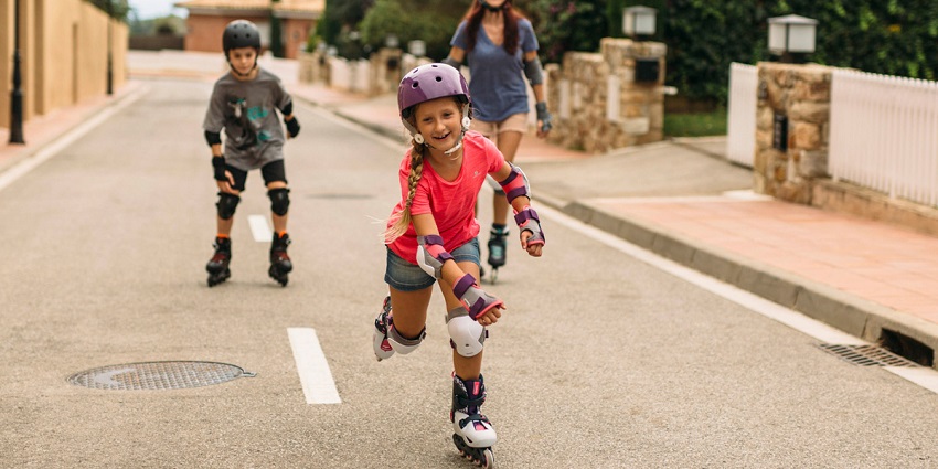 picture of two kids and a woman roller skating on the streets