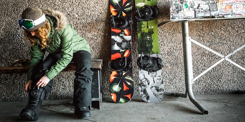 woman on bench tying her snowboard boots