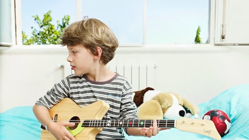 boy is playing on children's musical instruments - loog guitar 