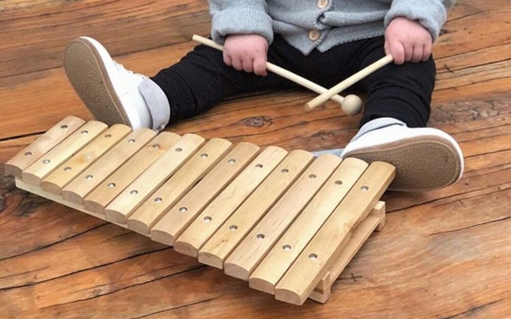 kid playing on wooden xylophone 