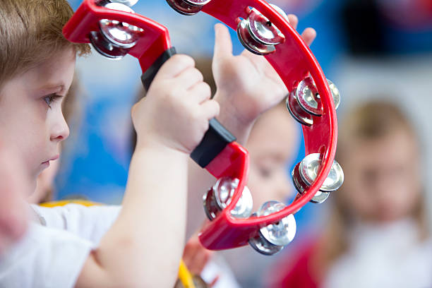 Close up of a little boy playing with a tambourine at school.