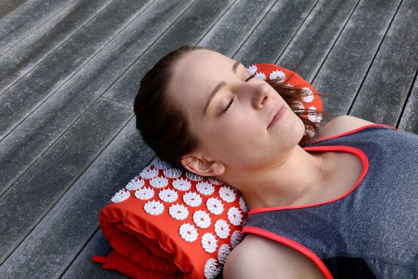 girl massaging her neck on shakti mat